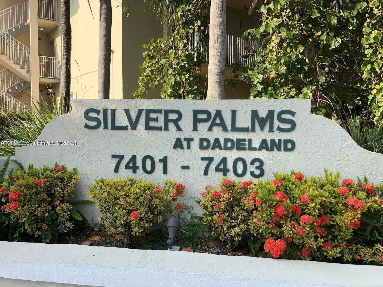 Stucco monument sign for Silver Palms at Dadeland, framed by flowering shrubs and native landscaping