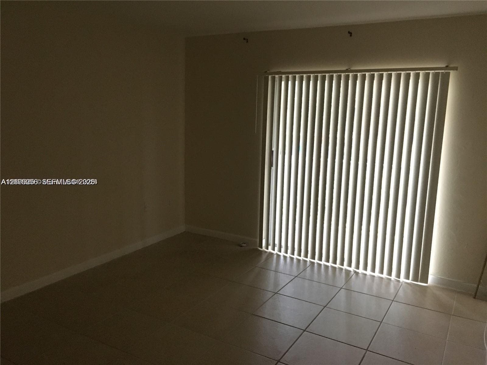 Interior space featuring large-format neutral tile flooring and sliding glass door with vertical blinds