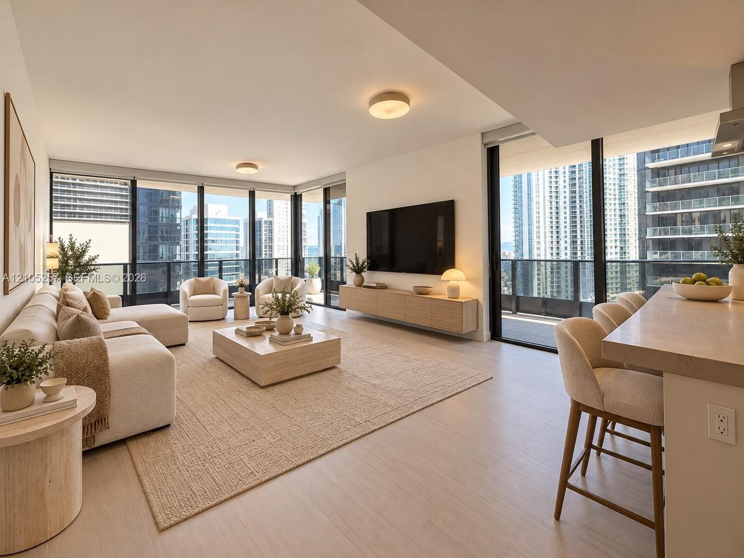 Open-concept living space featuring floor-to-ceiling windows, wood-finish flooring, a wall-mounted floating media console, and a kitchen island with a stone-finish countertop