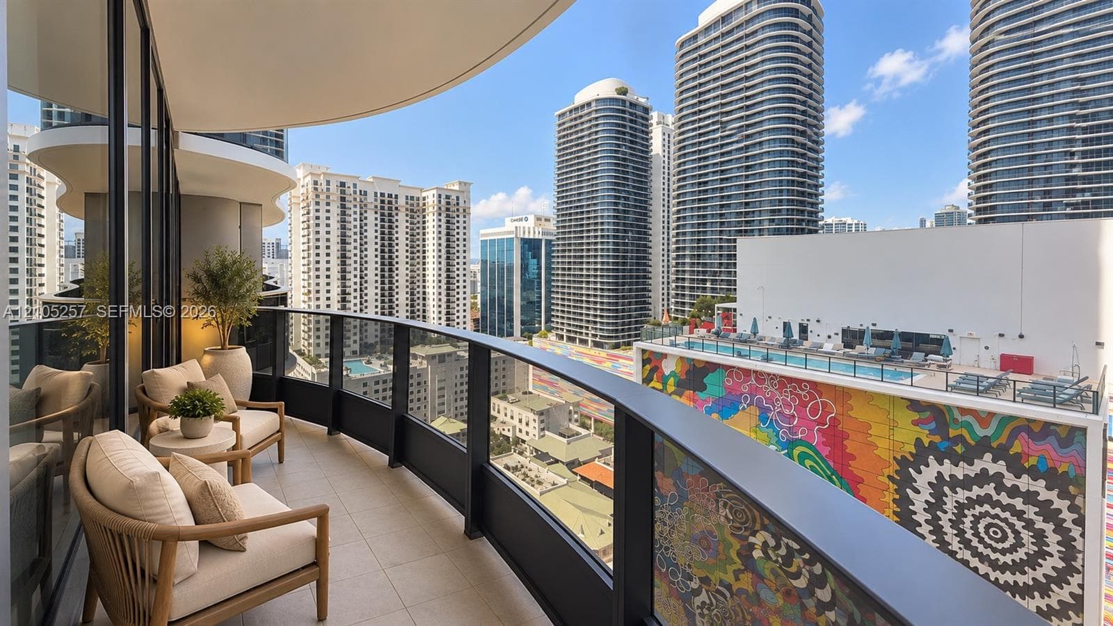Curved private balcony featuring tile flooring and a black metal railing with glass panels