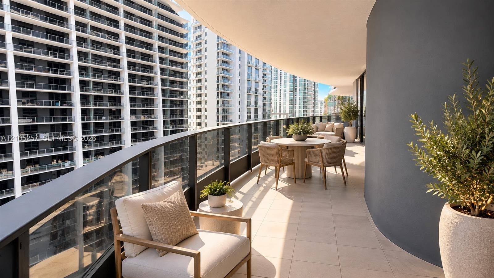 Expansive covered balcony featuring large-format tile flooring, a curved exterior wall, and a full-length glass railing