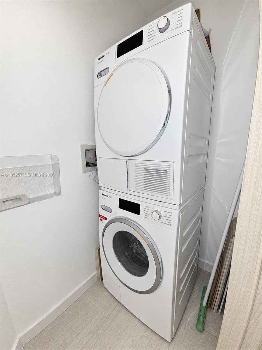 Stacked white front-loading laundry unit with integrated control panels and recessed wall shelving