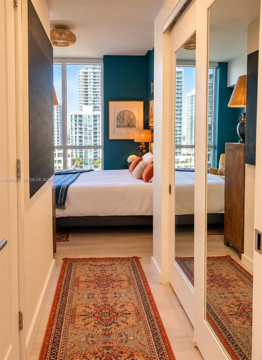 Floor-to-ceiling windows, wood-finish flooring, and sliding mirror-panel closet doors