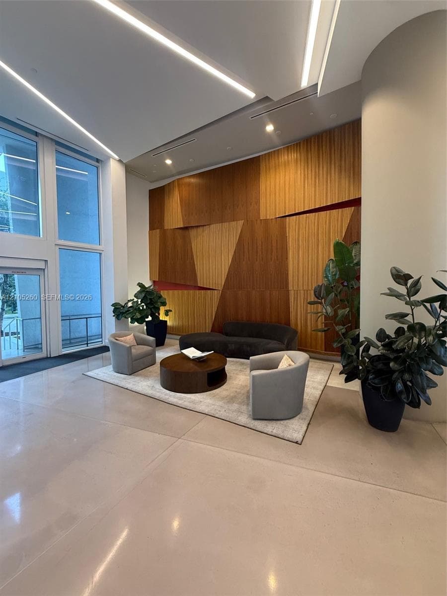 Hardwood accent wall with geometric design, recessed lighting, floor-to-ceiling windows, and polished concrete flooring