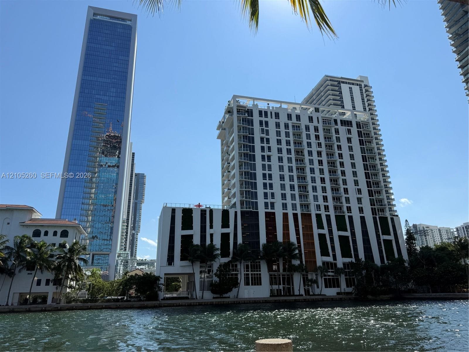 High-rise building featuring a white facade, vertical architectural accents, private balconies, and waterfront positioning