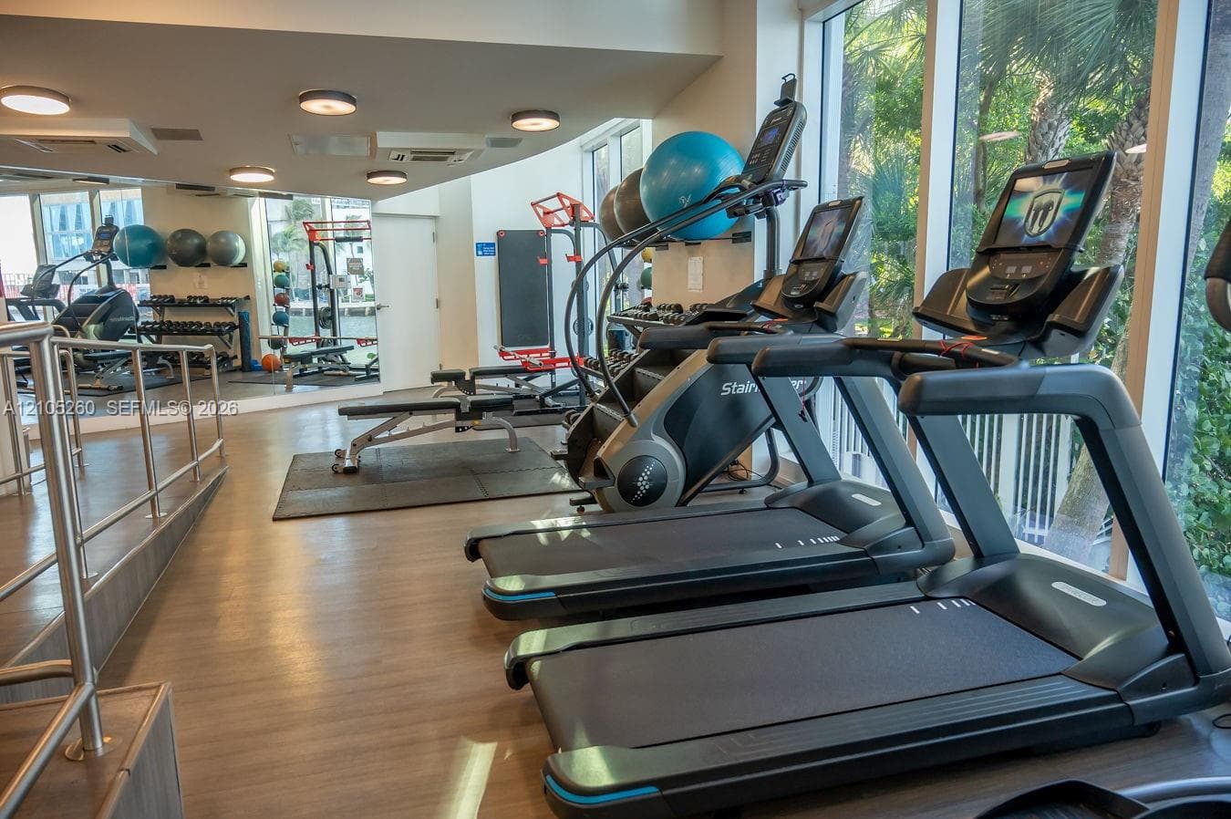 Fitness center featuring wood-finish flooring, ample natural light through expansive windows, and integrated ceiling lighting
