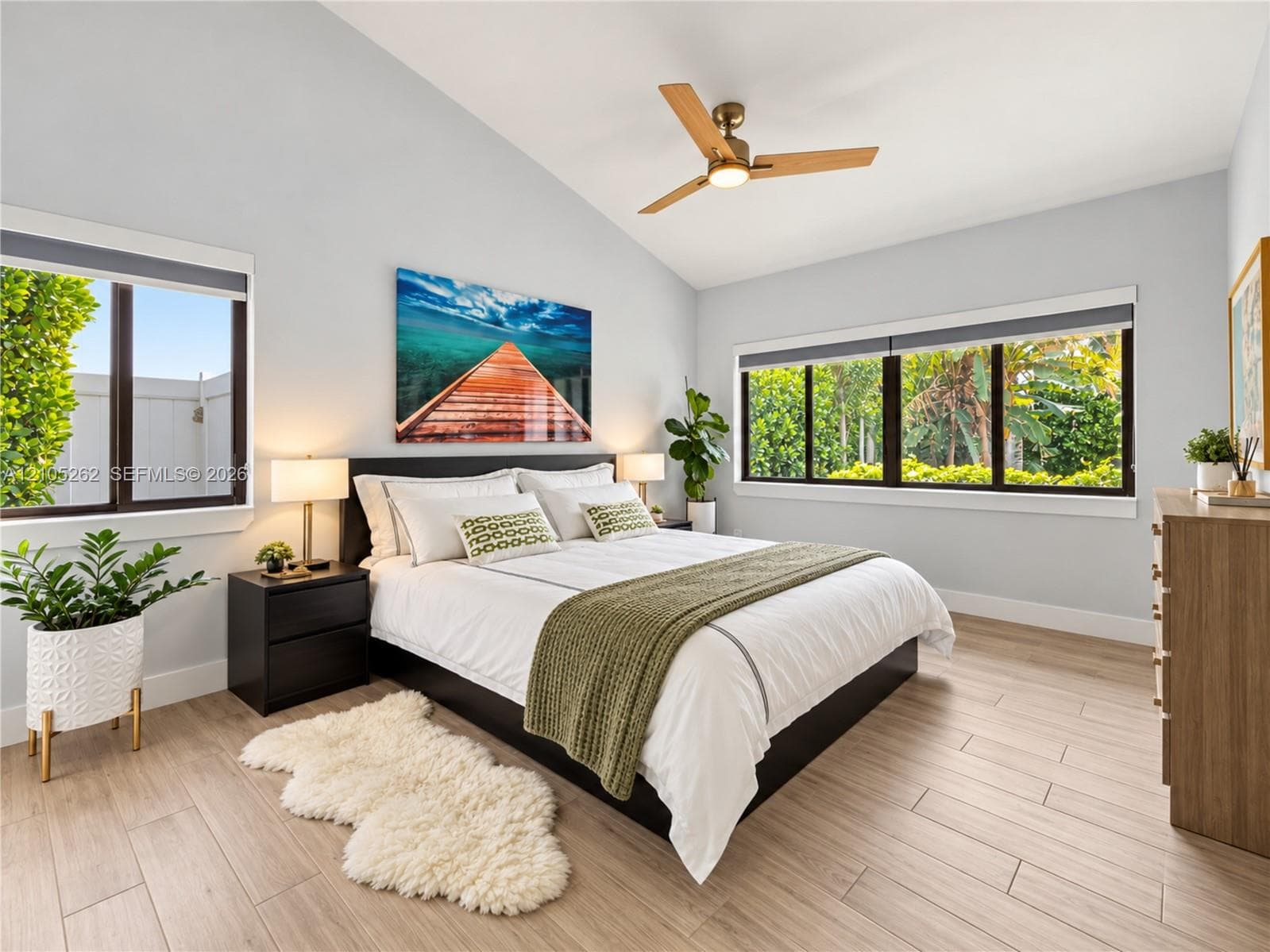 Vaulted ceiling, ceiling fan with integrated lighting, wood-finish flooring, two large windows, and a single window