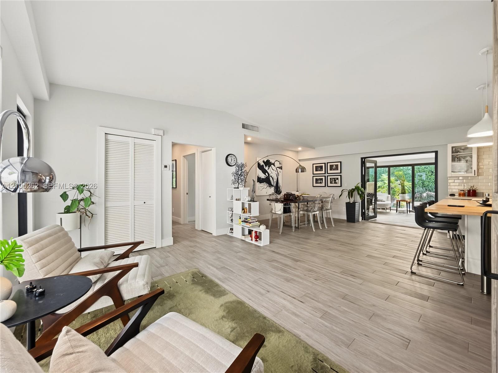 Wood-finish flooring throughout, integrated kitchen island with breakfast bar, bi-fold patio doors, and a vaulted ceiling