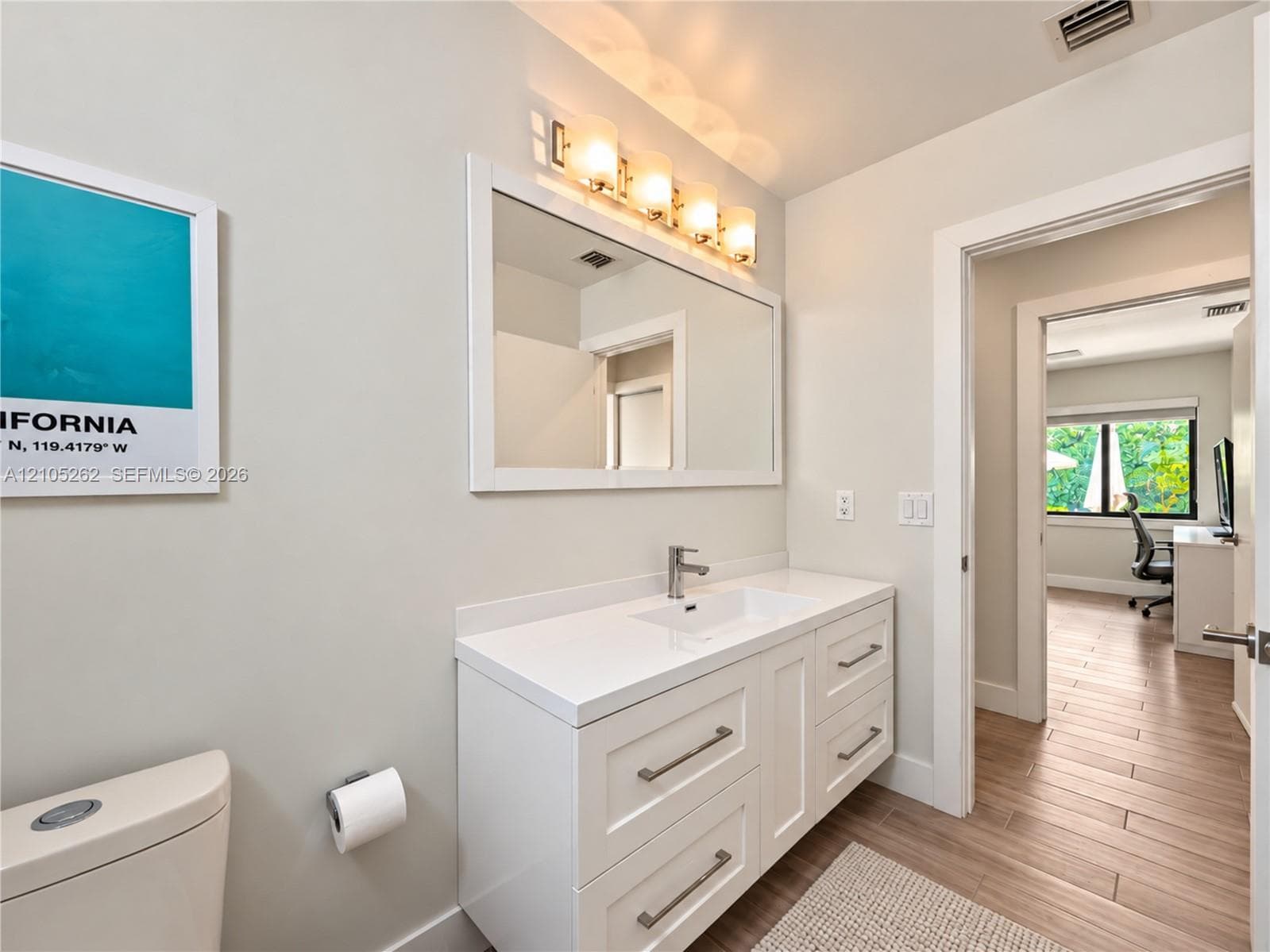 White vanity with ample storage drawers, sleek countertop, and integrated sink