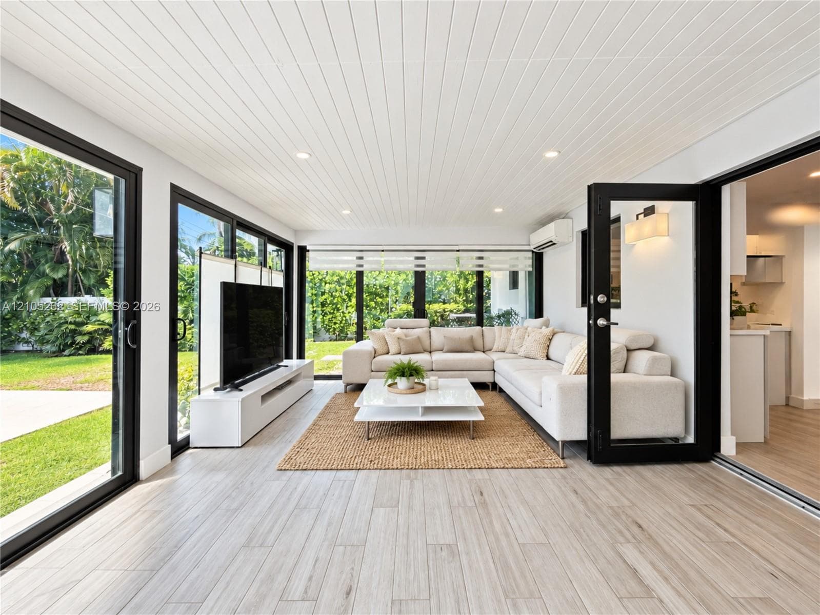 Wood-finish plank flooring, slatted ceiling, recessed lighting, and black-framed glass sliding doors