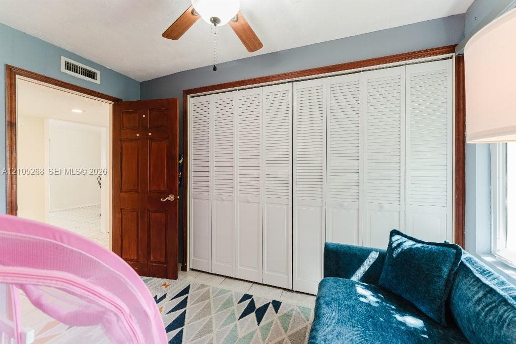 Wood-finish ceiling fan, recessed lighting, wood-finish paneled door, and white louvered bifold closet doors