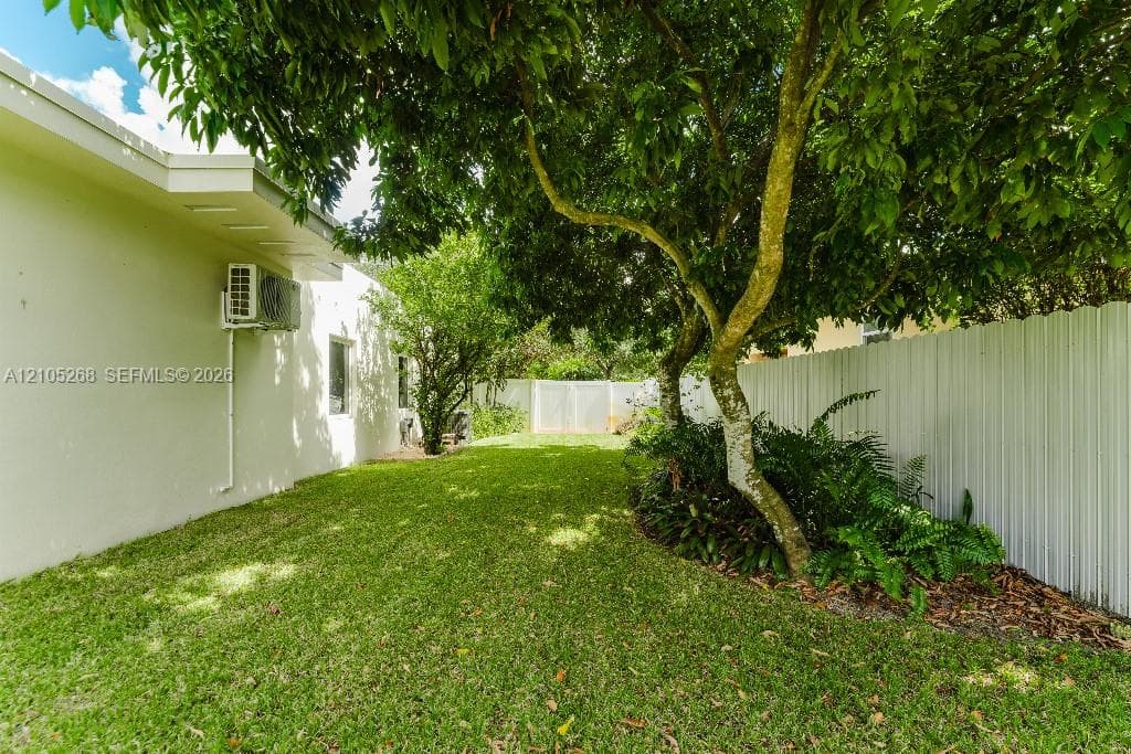 Expansive lawn area with mature trees and perimeter fencing