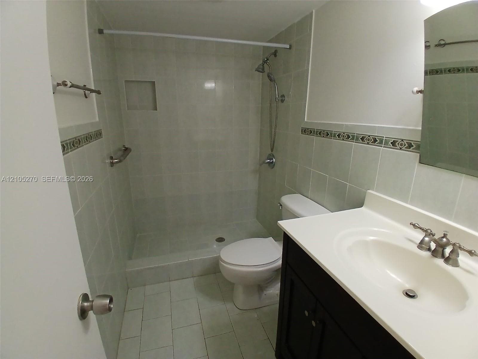 Tiled shower with a built-in niche, chrome shower fixtures, and a grab bar