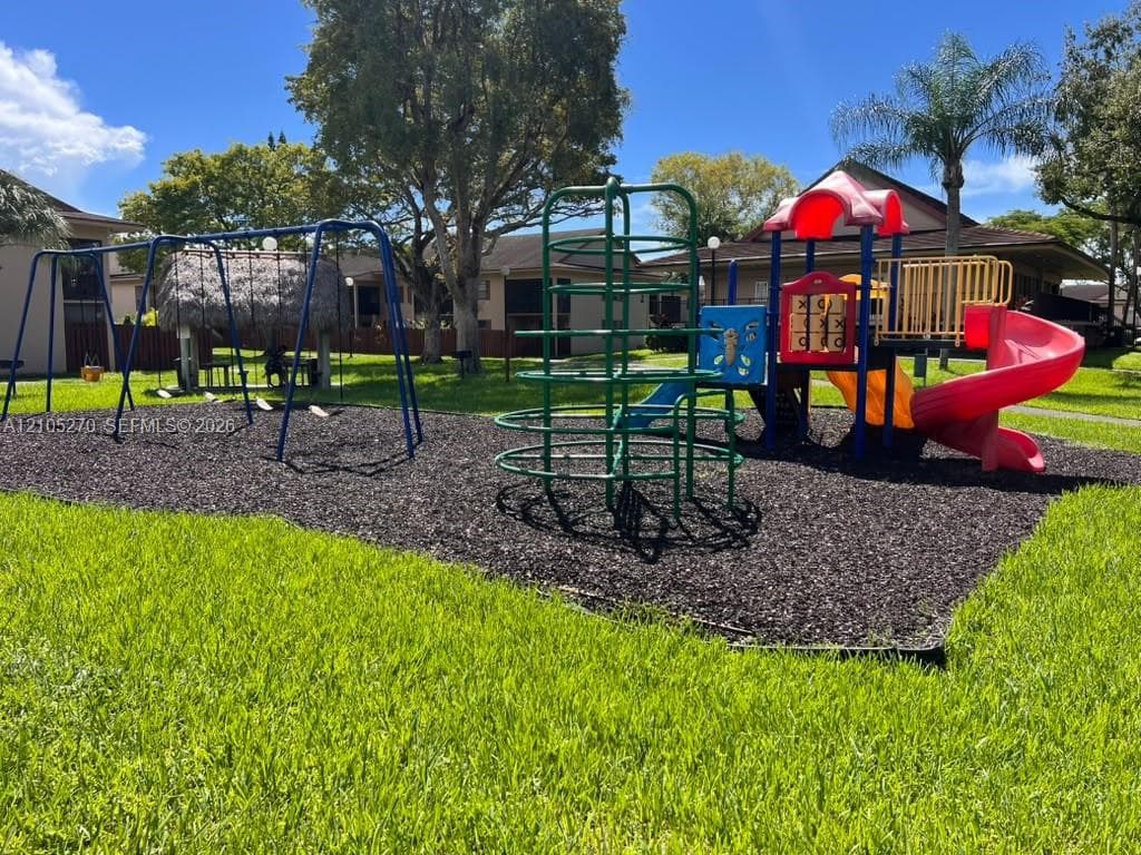 Expansive green lawn with a children's play structure featuring slides and swings