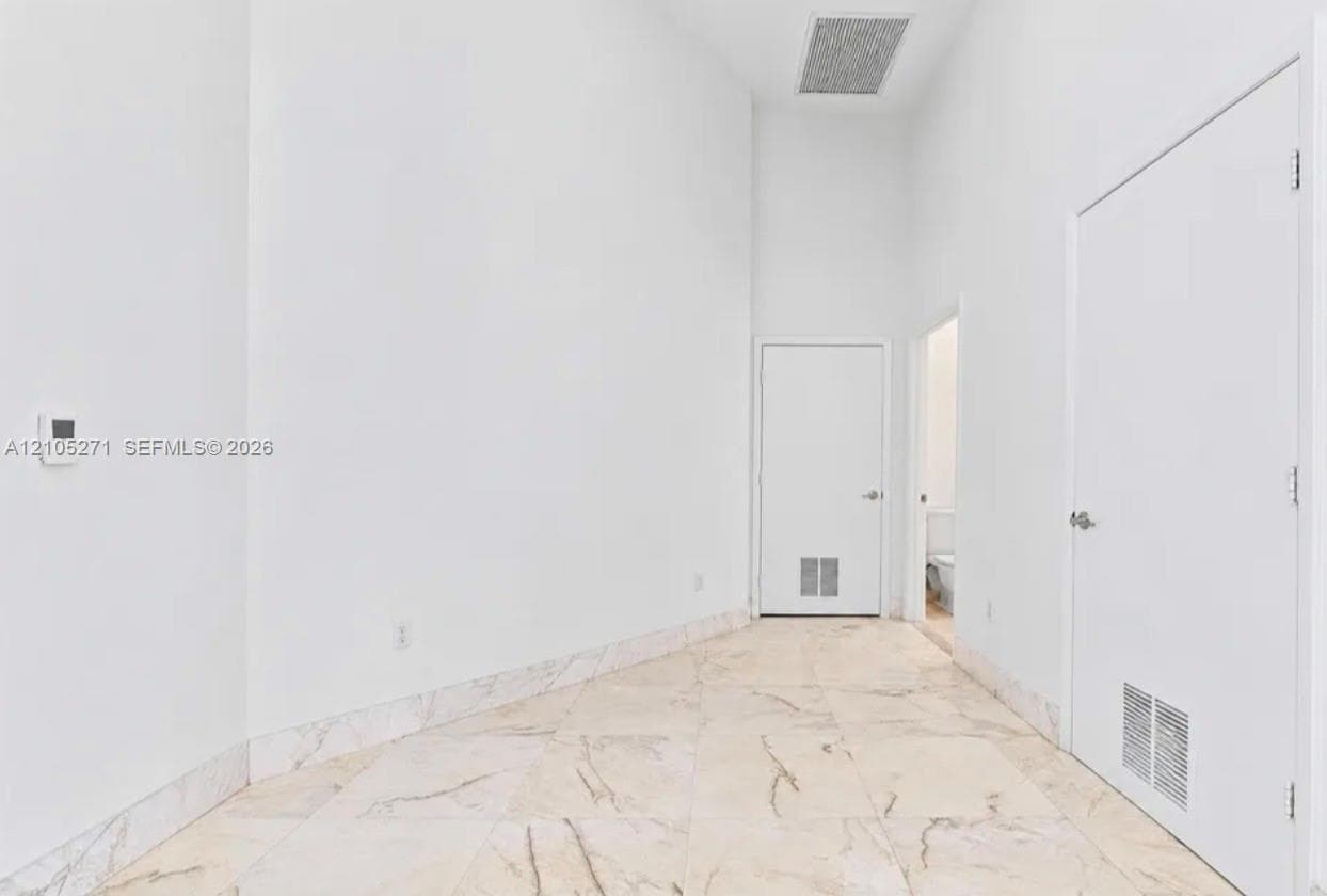 High-ceiling interior featuring polished stone tile flooring and stone tile wainscoting