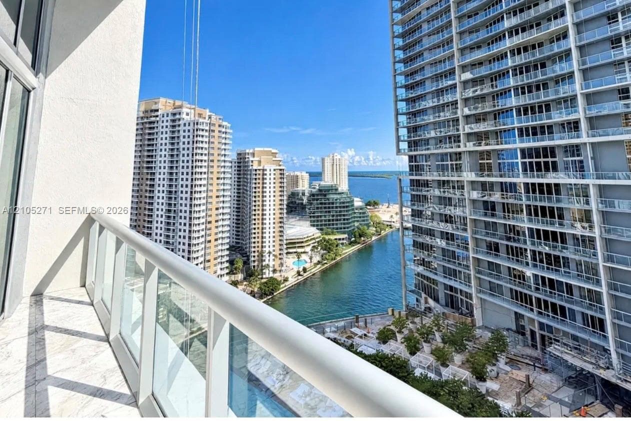 Private balcony featuring stone tile flooring and a glass-paneled railing