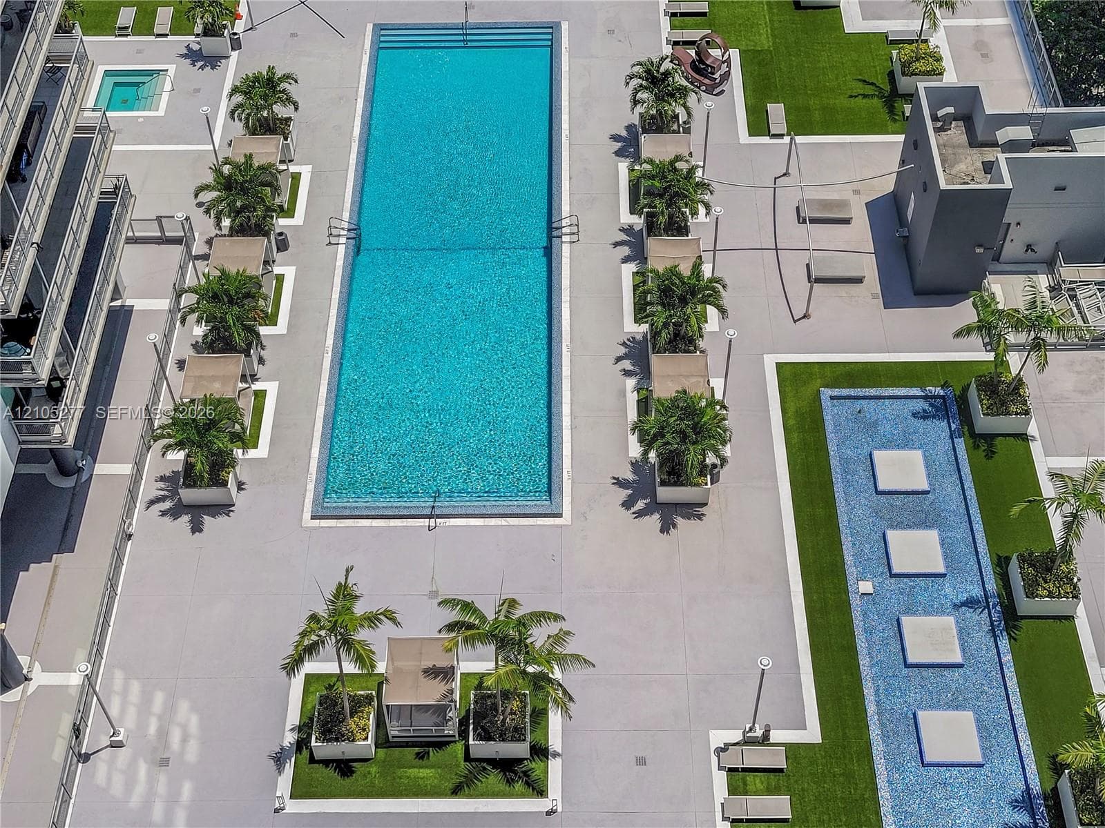 Expansive outdoor amenity deck featuring a swimming pool, spa, and decorative water feature