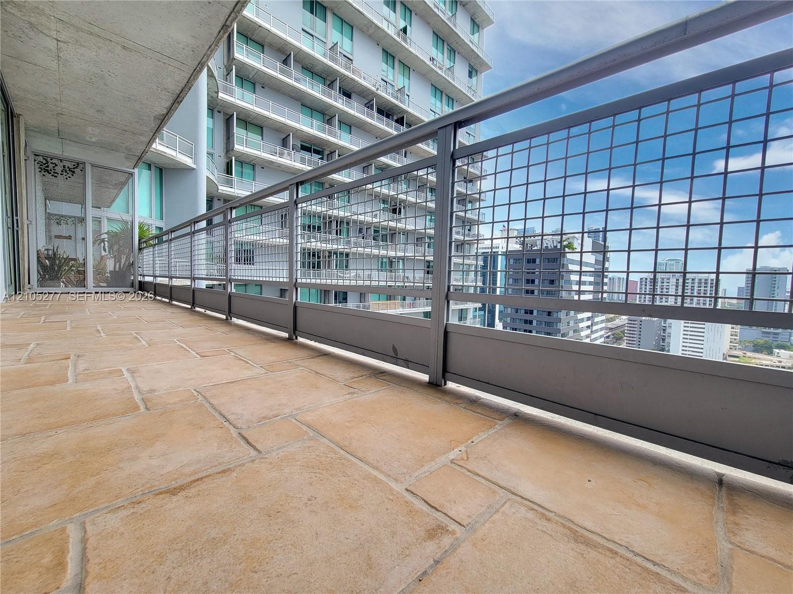 Expansive balcony featuring large format tile flooring and metal grid railing