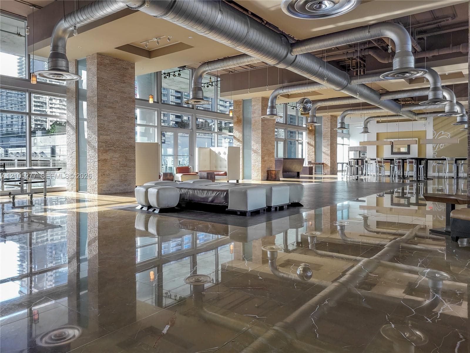 Expansive common area featuring polished flooring, exposed ductwork, and abundant natural light