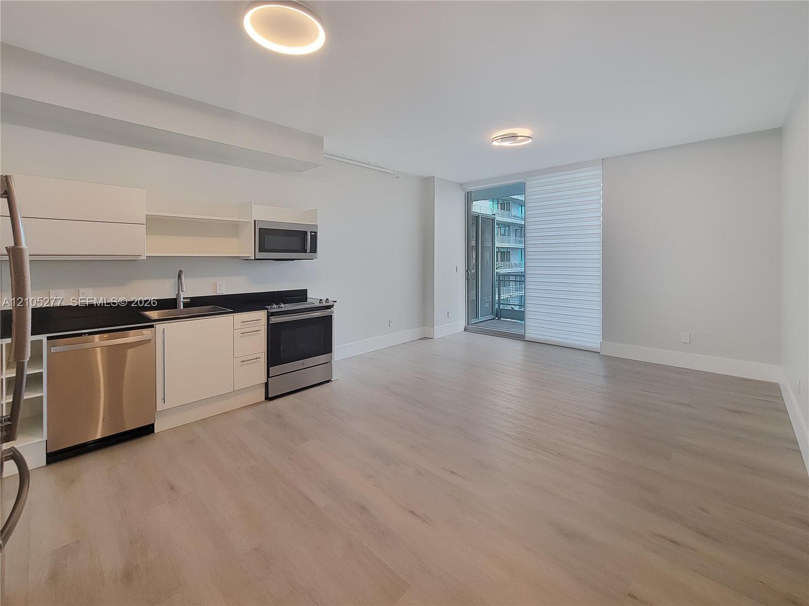 Kitchenette with stainless steel appliances, dark countertops, and white cabinetry
