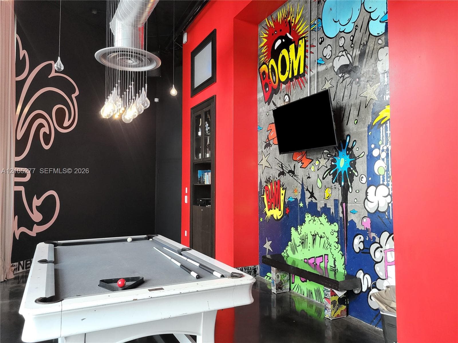 Contemporary interior featuring high ceilings, exposed ductwork, a decorative wall mural, and dark flooring