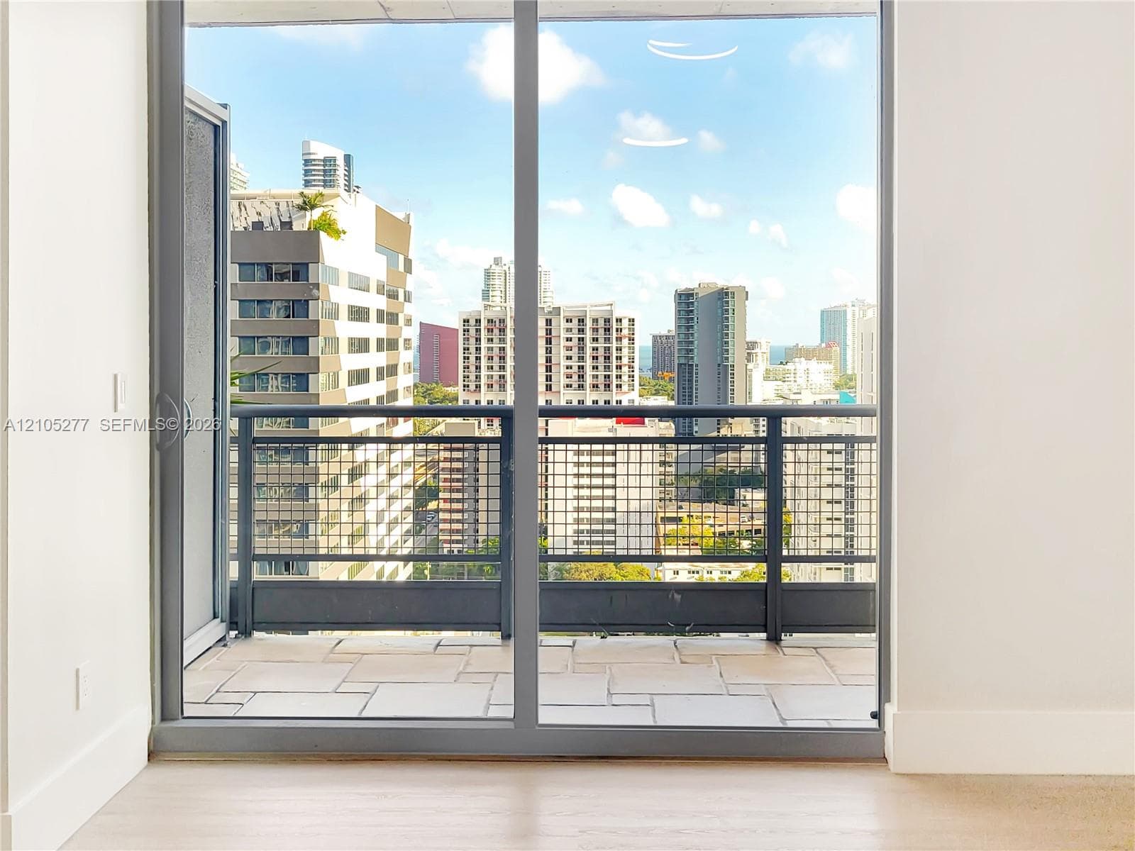 Floor-to-ceiling sliding glass doors opening to a private balcony with metal railings and paver flooring