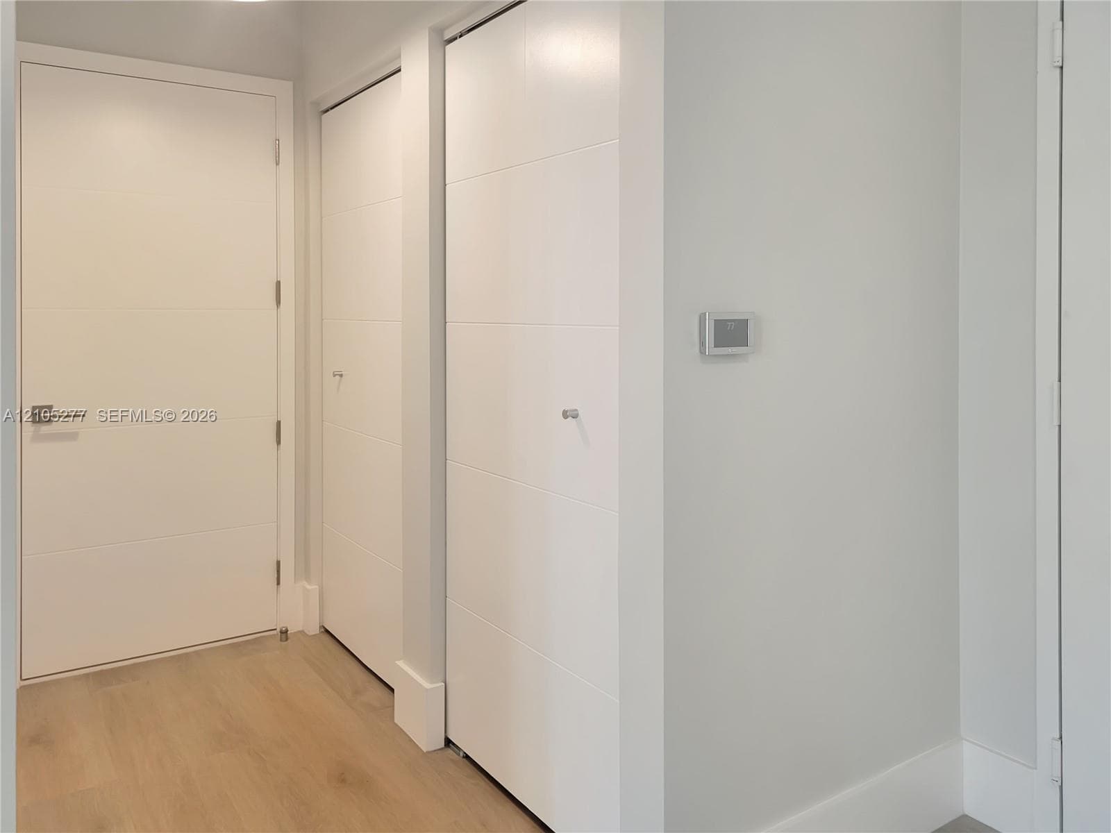 Light-toned wood-finish flooring with white baseboards