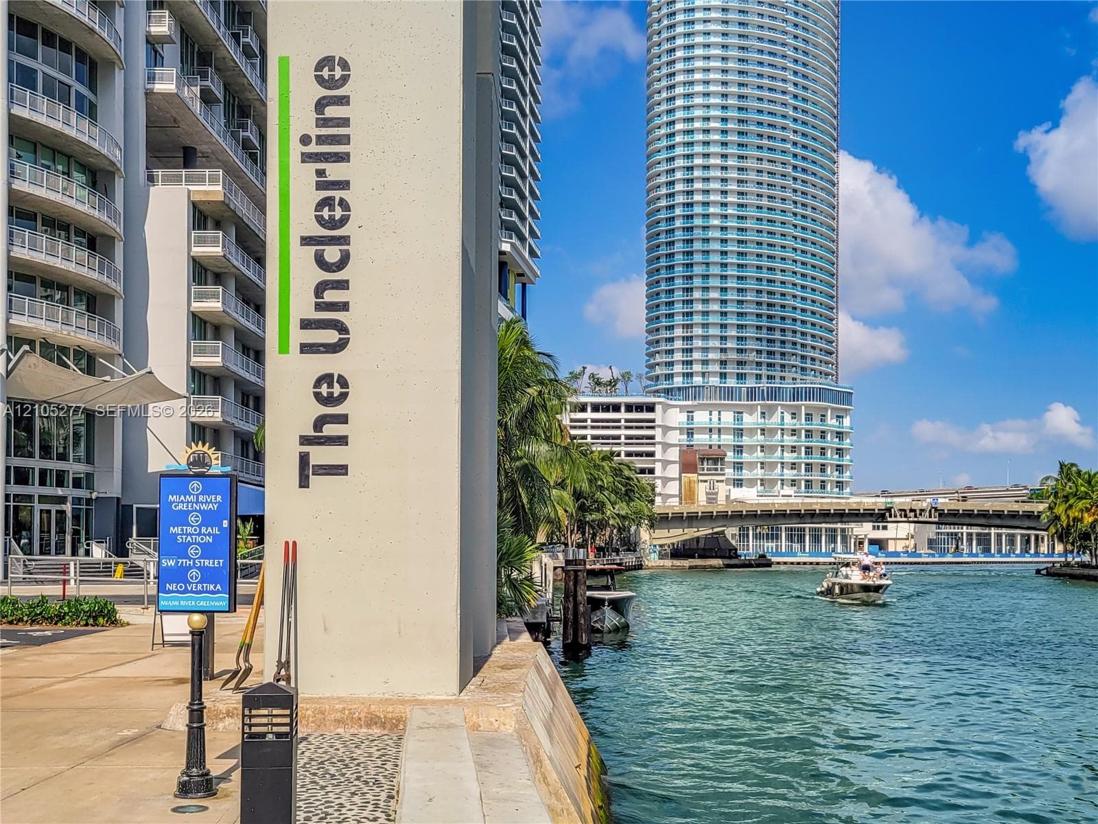 Waterfront setting featuring a prominent high-rise building and a waterway with a boat