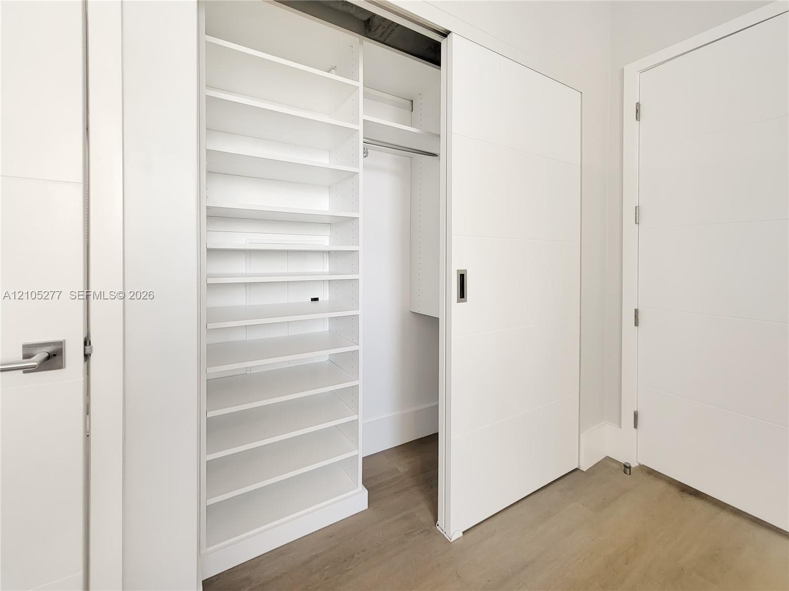 White built-in shelving, sliding closet door, and wood-finish flooring