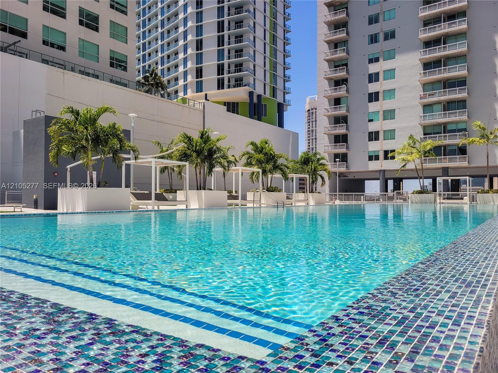 Expansive swimming pool with blue and white mosaic tile surround