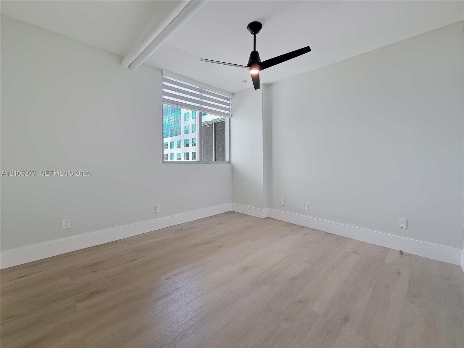Neutral wall tones, wood-finish flooring, contemporary ceiling fan, window with horizontal blinds, and a roller shade system