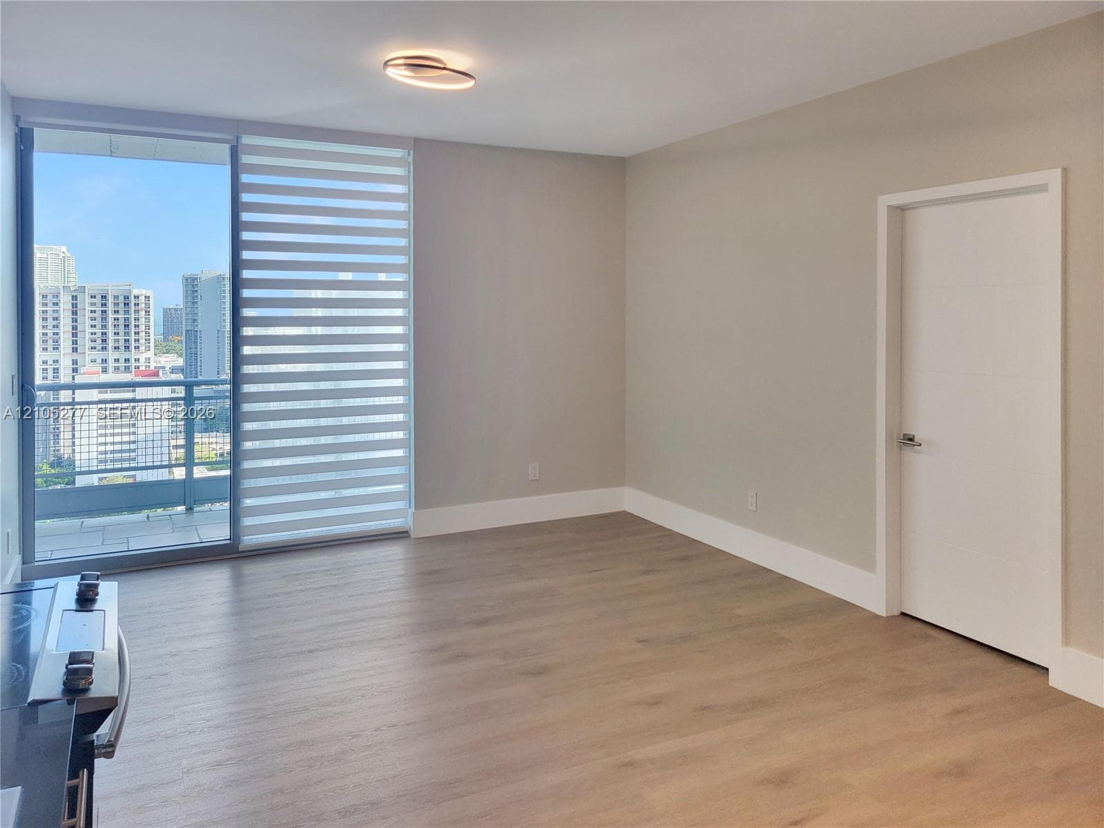 Wood-finish flooring, a contemporary ceiling light fixture, a sliding glass door, and a private balcony
