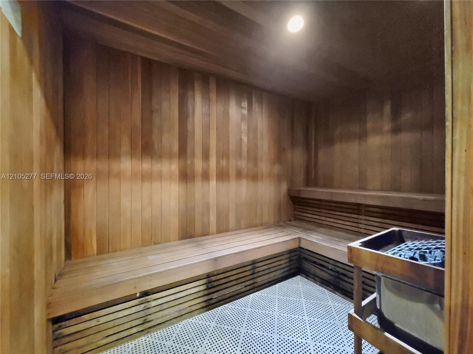 Cedar-lined sauna featuring L-shaped bench seating, integrated heater, and textured floor
