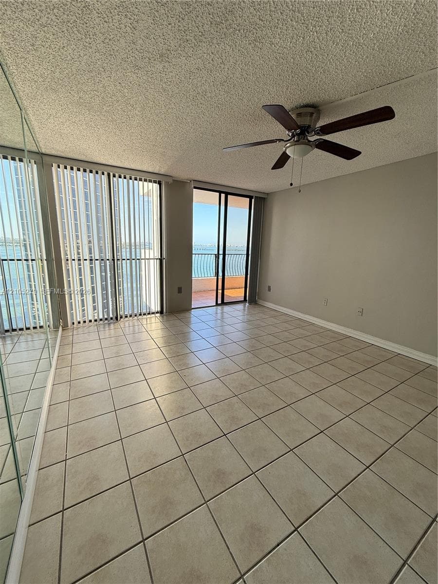 Tile flooring throughout, full-length mirrored wall, ceiling fan with integrated lighting, and sliding glass doors to outdoor area