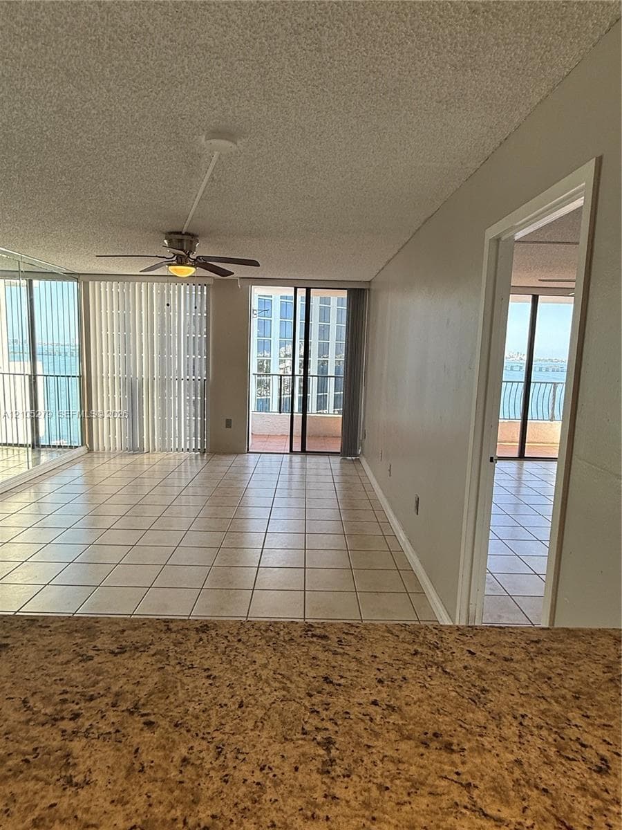 Tile flooring throughout, with a ceiling fan in the living area, and an exterior balcony