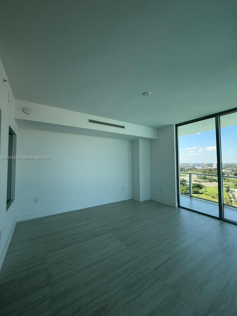 Floor-to-ceiling glass sliding doors, private balcony, wood-finish tile flooring, recessed ceiling HVAC, and neutral wall finishes