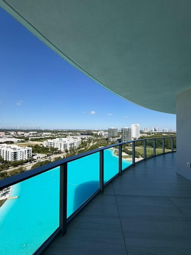 Curved balcony featuring large-format tile flooring and a glass panel railing with a dark metal frame