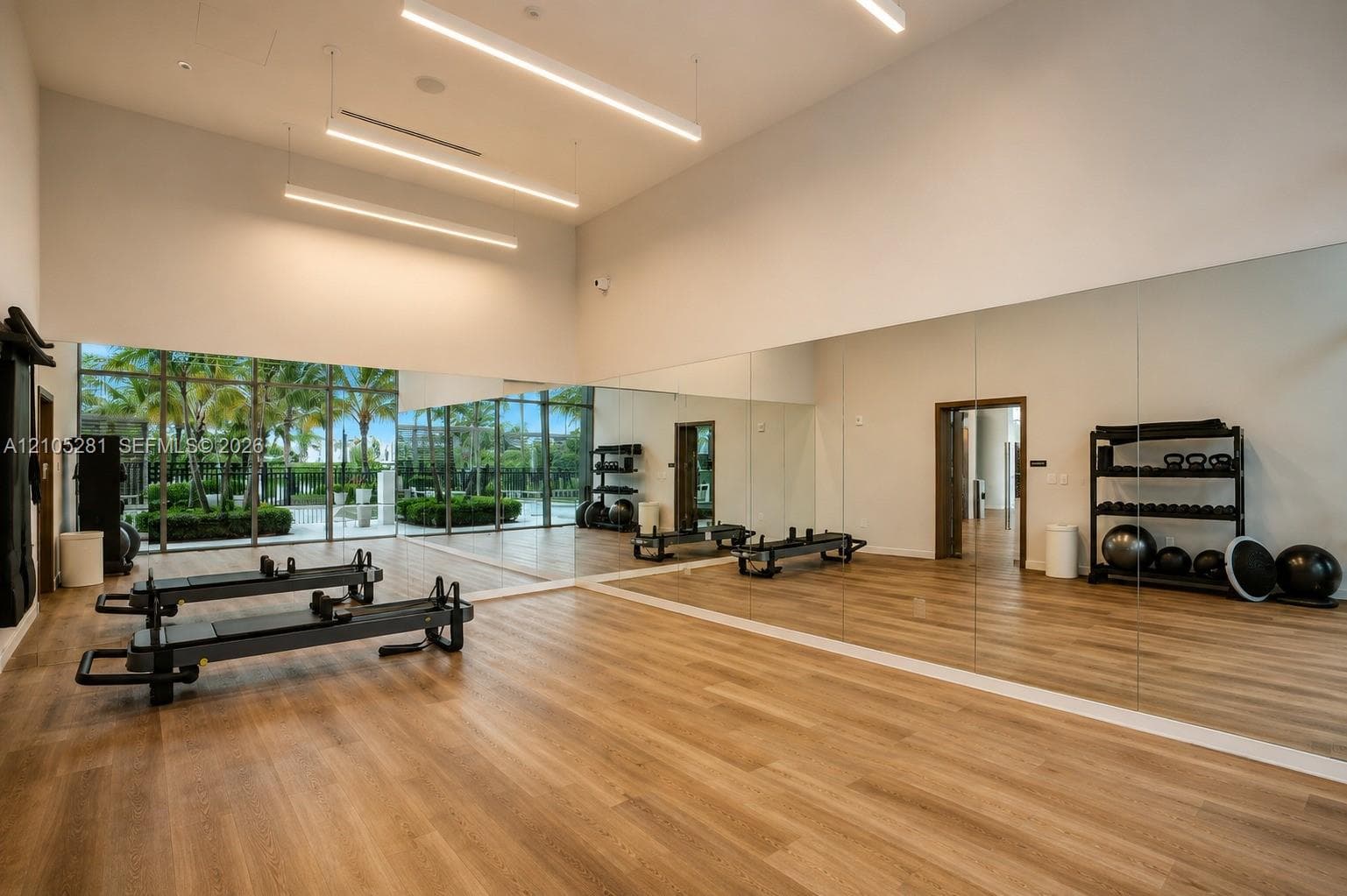 Fitness space featuring high ceilings, floor-to-ceiling mirrors, wood-finish flooring, linear LED lighting, and expansive glass window walls