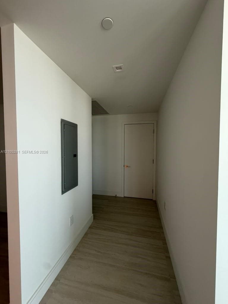 Hallway featuring wood-finish flooring, recessed ceiling lighting, and a flush-mounted solid-core door