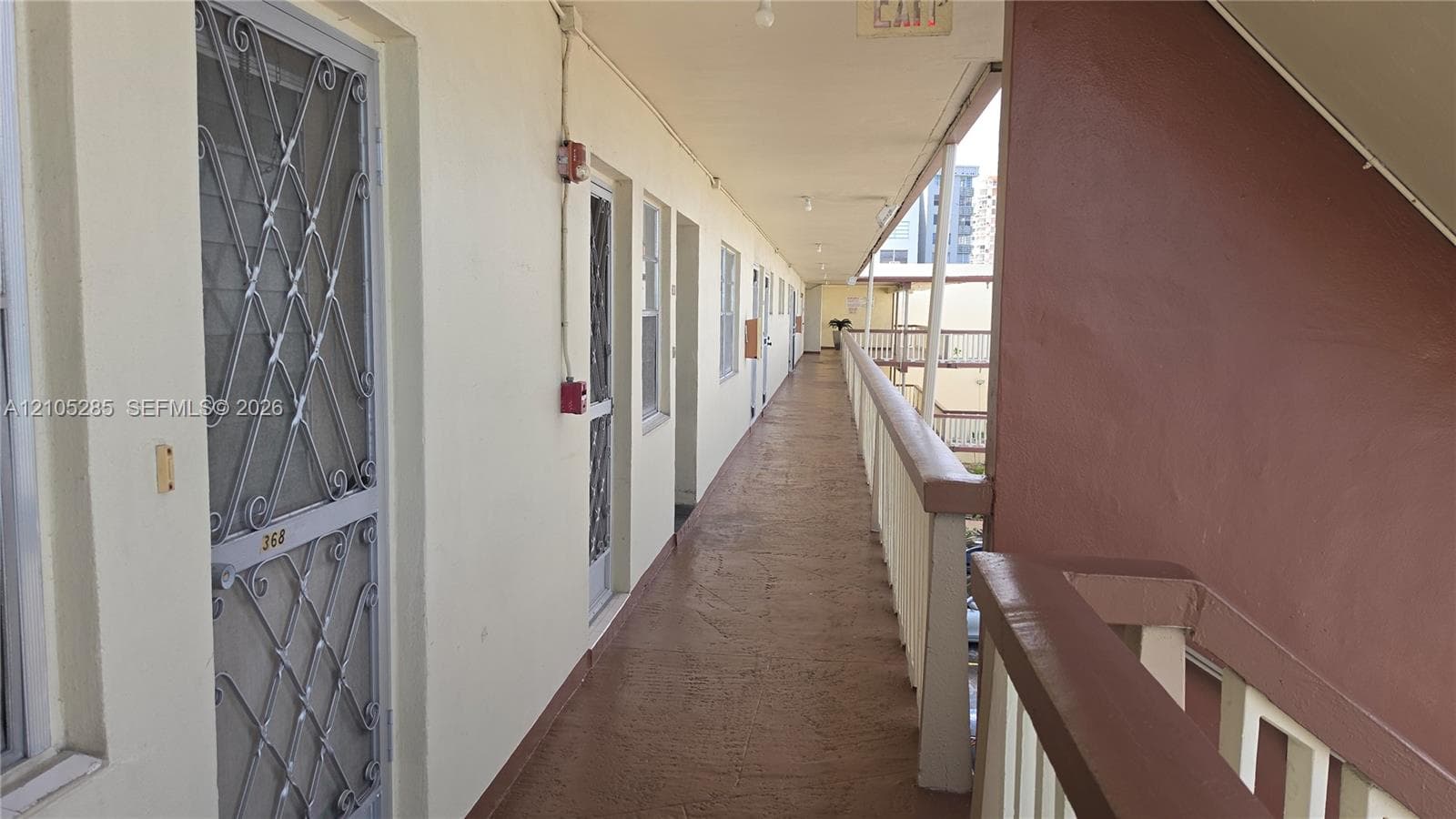 Exterior covered walkway featuring decorative metal security screen doors and a painted handrail