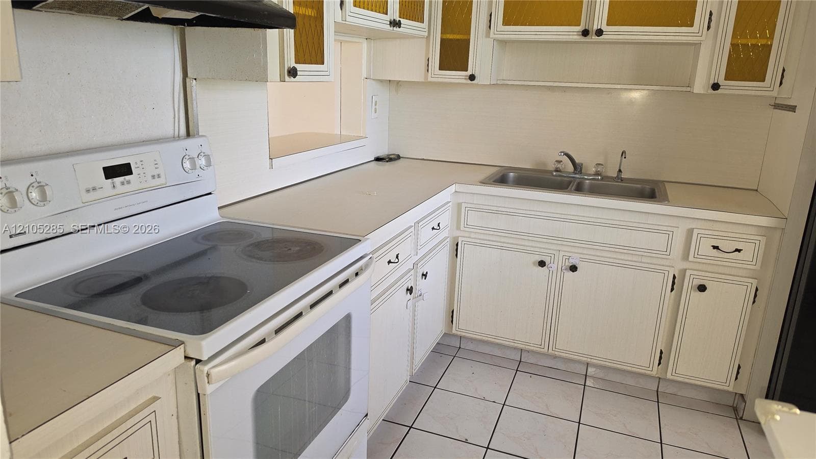 Kitchen featuring white cabinetry, solid-surface countertops, dual-basin stainless steel sink, tile flooring, and a white electric range