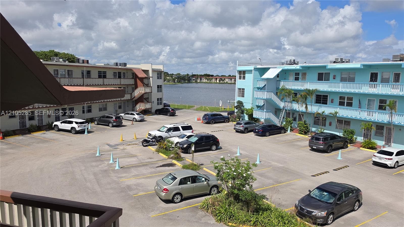 Multi-story residential complex featuring designated surface parking, metal exterior staircases, and open-air corridors overlooking a lakefront setting