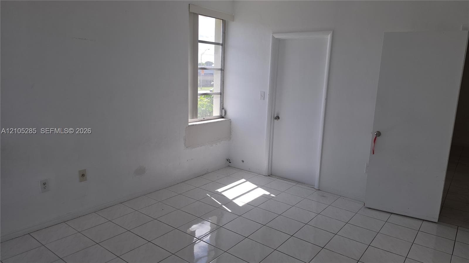 Interior space featuring light-colored tile flooring, white-painted walls, and a single-pane window
