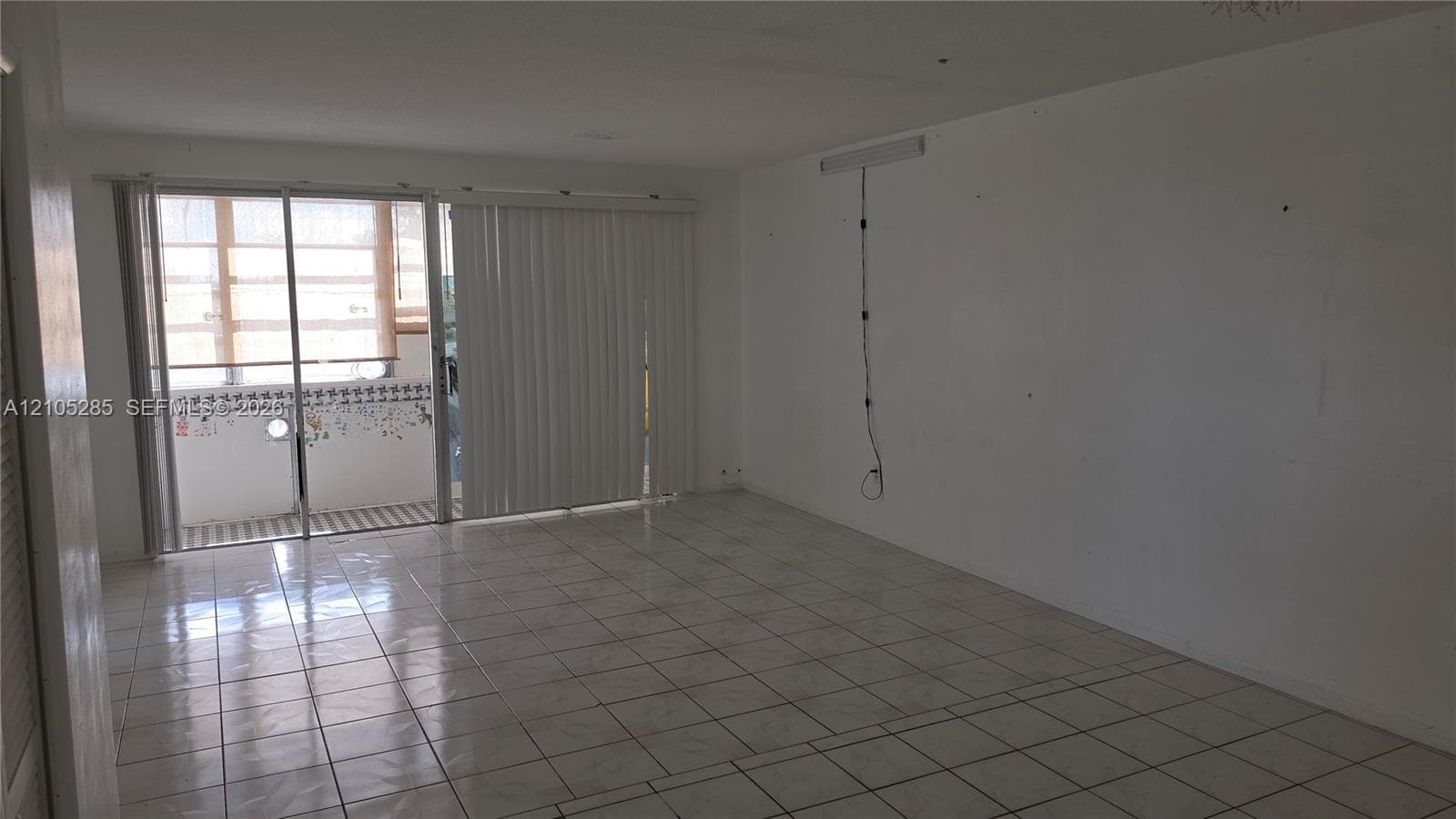 Interior space featuring neutral wall tones, large-format tile flooring, and a floor-to-ceiling sliding glass door