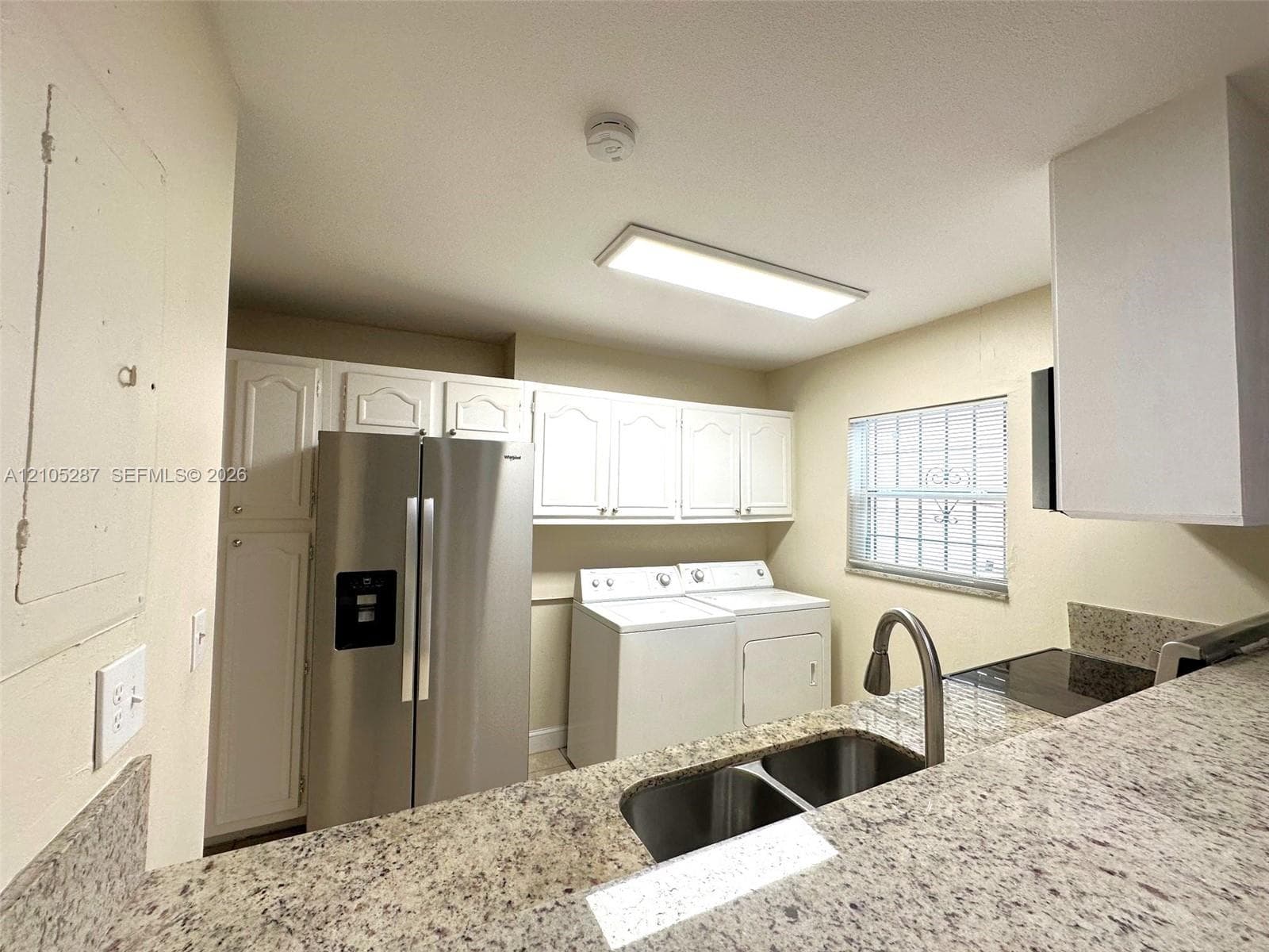 Kitchen with white cabinetry, a double basin sink, and light-toned countertops