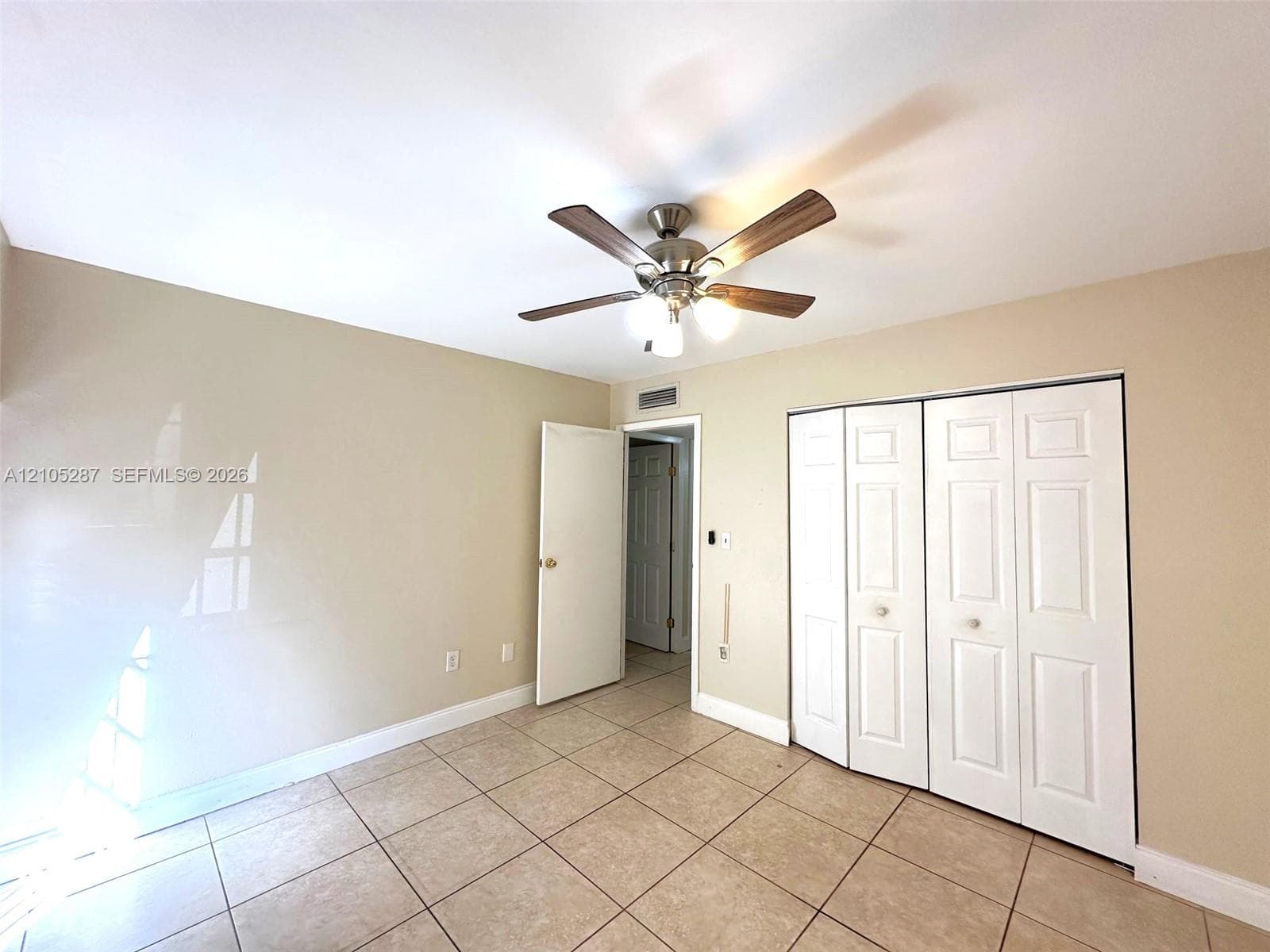 Neutral-toned walls, tile flooring, and a ceiling fan with integrated lighting