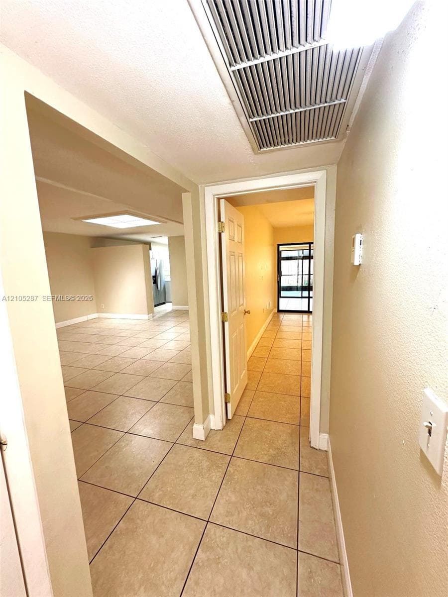 Tile flooring in a neutral tone, recessed lighting, and a white interior door