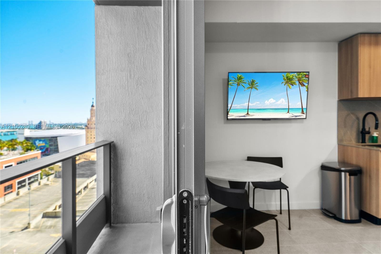 Balcony with glass railings, kitchen with wood-finish cabinetry, stainless steel sink, and black faucet