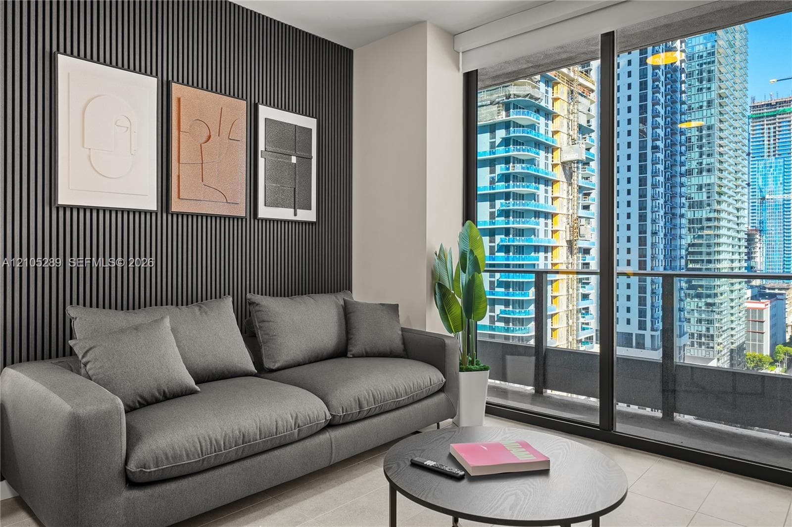 Floor-to-ceiling glass doors, private balcony, city skyline backdrop, modern slat wall paneling, light-toned flooring