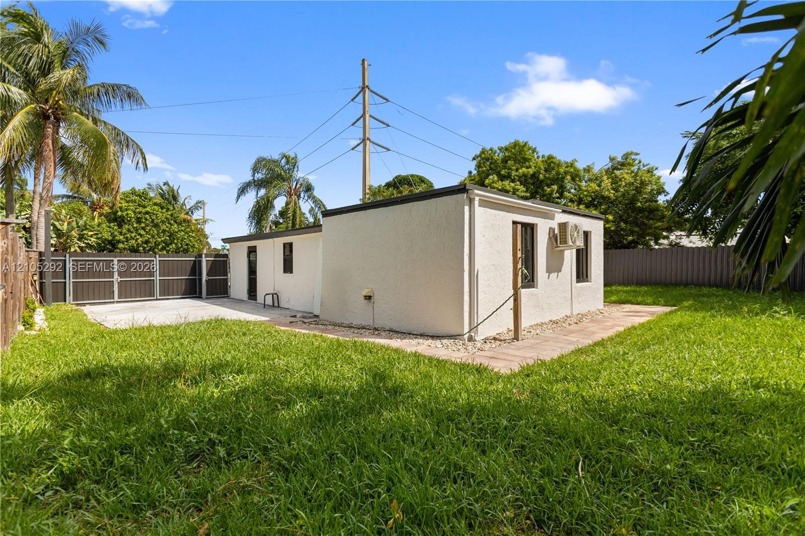 Enclosed yard with a privacy fence, concrete patio, and mature landscaping
